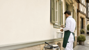 Maler streicht eine helle Fassade an einem Wohnhaus in Bamberg